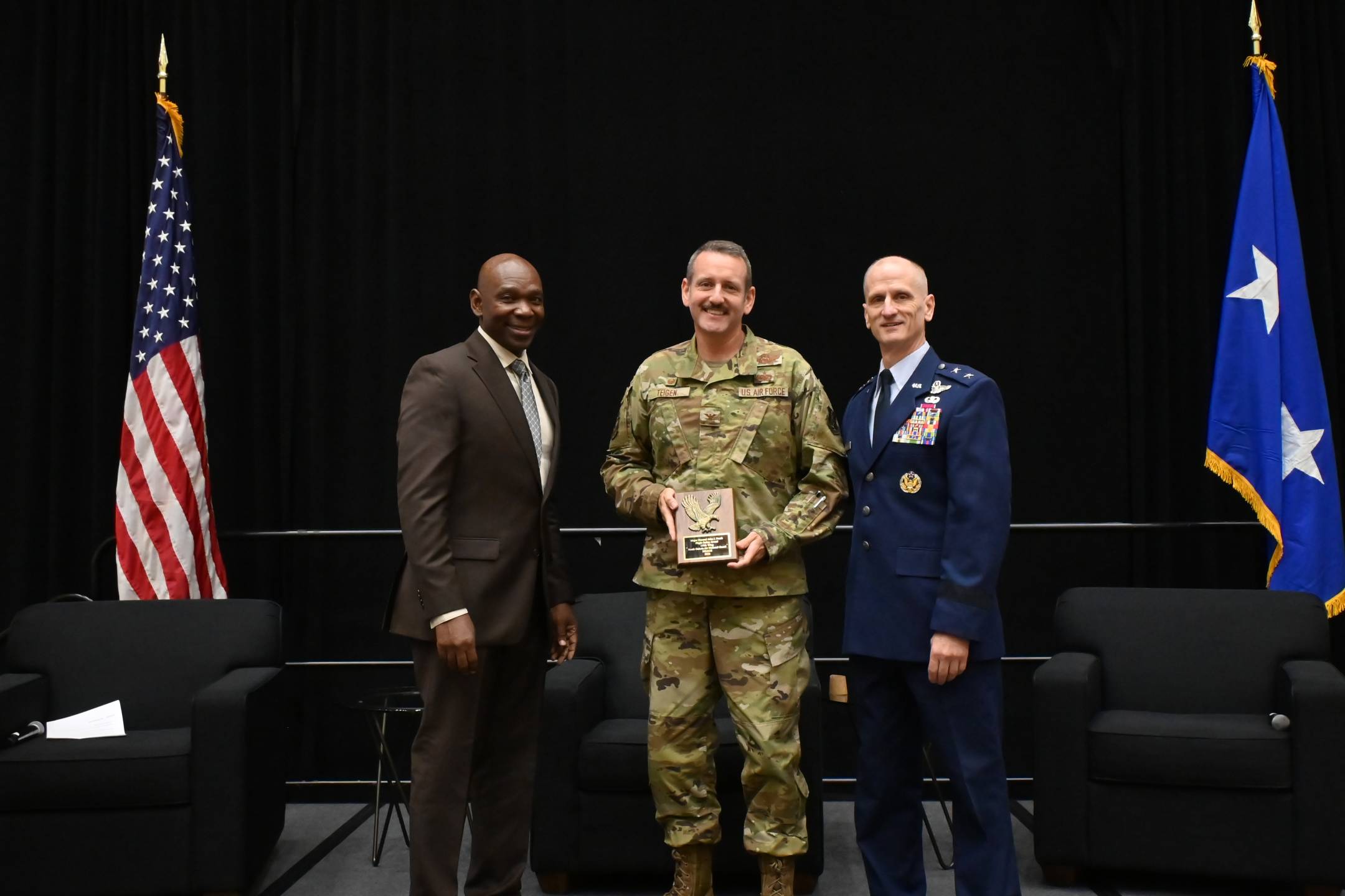 U.S. Air Force Col. Lee Teigen, commander, 119th Operations Group, 119th Wing, North Dakota Air National Guard, receives the Maj. Gen. John J. Pesch Flight Safety Trophy from (left) retired Maj. Gen. Ondra Berry, NGAUS vice chair-Air, and (right) U.S. Air Force Maj. Gen. Randy Efferson, the acting director of the Air National Guard, at the 148th NGAUS General Conference & Exhibition, Indianapolis, Indiana, August 31, 2026.