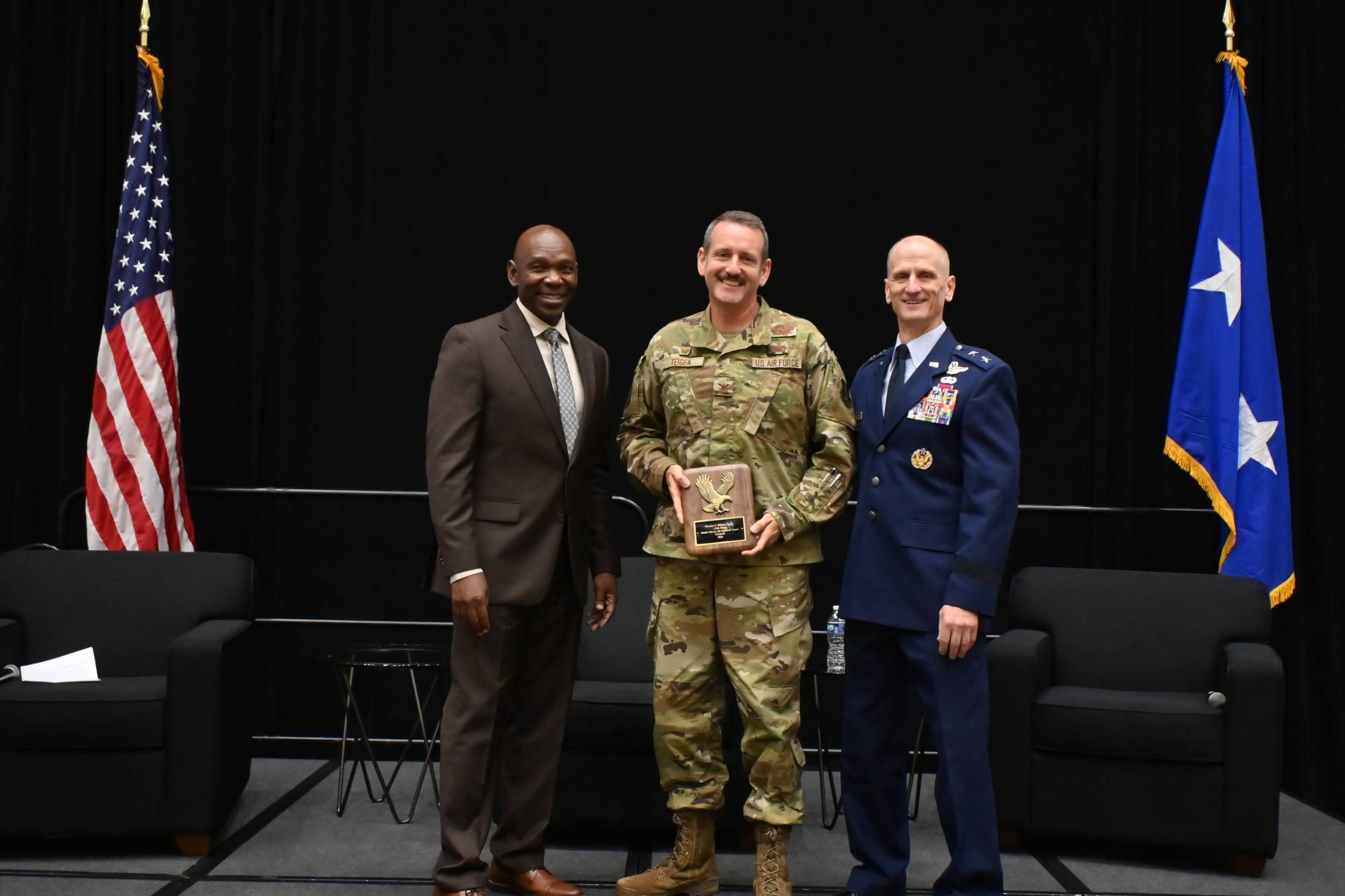 U.S. Air Force Col. Lee Teigen, commander, 119th Operations Group, 119th Wing, North Dakota Air National Guard, receives the Winston P. Wilson Trophy from (left) retired Maj. Gen. Ondra Berry, NGAUS vice chair-Air, and (right) U.S. Air Force Maj. Gen. Randy Efferson, the acting director of the Air National Guard, at the 148th NGAUS General Conference & Exhibition, Indianapolis, Indiana, August 31, 2026.   