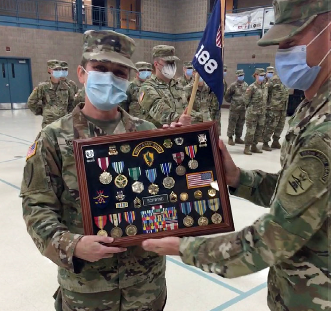 Chief Warrant Officer 2 James Landman presents Sgt. 1st Class Jennifer Schwind a shadow box displaying her awards and other items from her career during her retirement ceremony at weekend training of the 188th Army Band on July 17, 2020 at the Fargo Armed Forces Reserve Center. Schwind served with the North Dakota Army National Guard for over 20 years. (National Guard photo by Sgt. Taryn Benton, 188th Army Band)