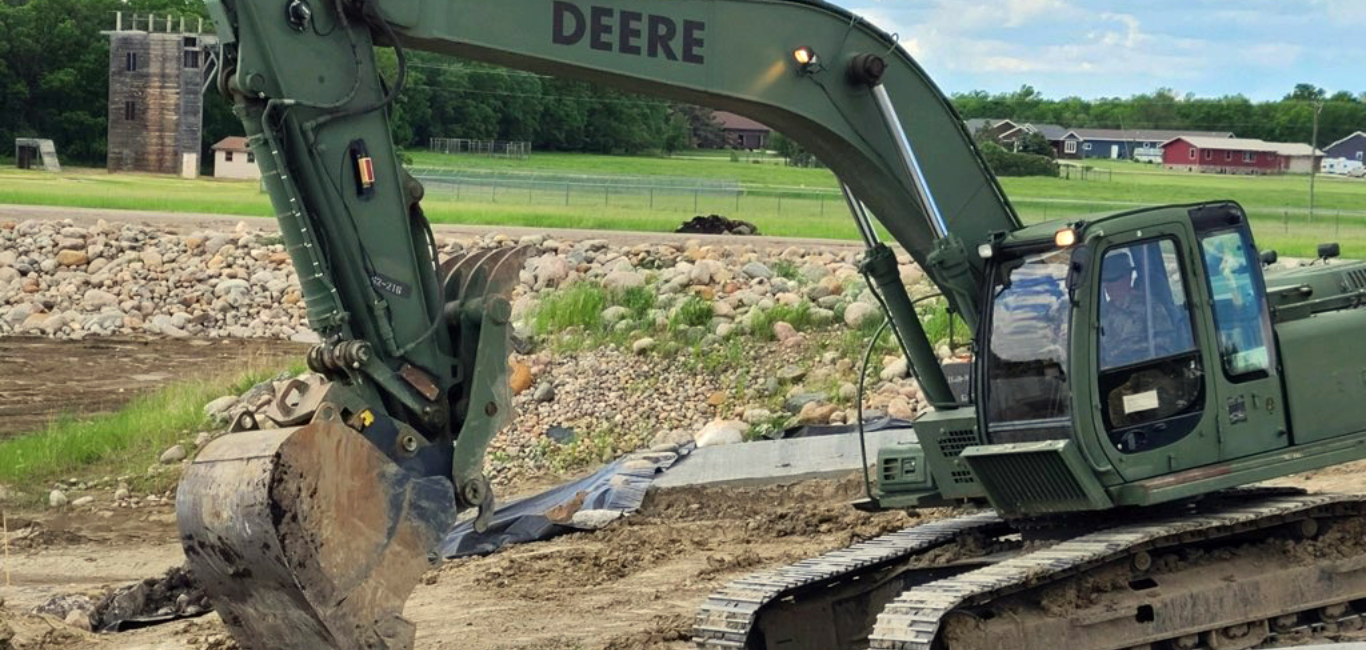 Sgt. 1st Class Jose Figueroa-Diaz, an instructor with the 164th Regional Training Institute, places rip rap rocks with a Hydraulic Excavator (HYEX) on June 11, 2020 near the boat launch pads at Richie Slough. The rocks help prevent erosion.