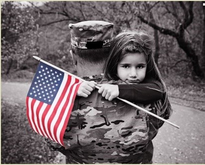 Picture of Soldier holding his daughter while she holds a flag