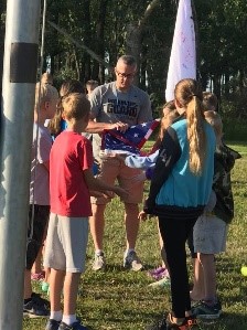 Children and adult folding a flag